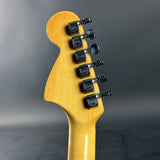 Guitar headstock with tuning pegs on a gray background