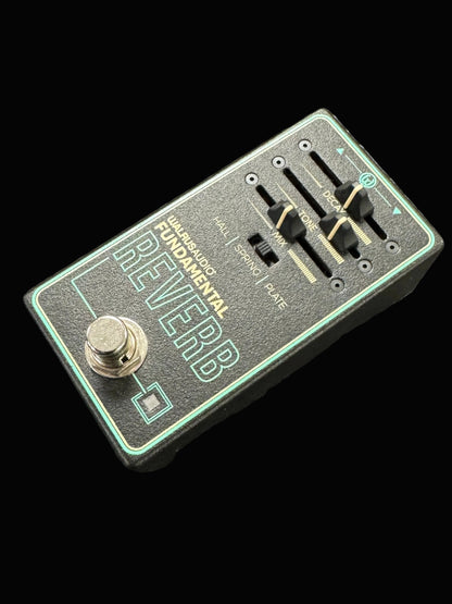 Guitar effects pedal with 'Reverb' text on a textured surface