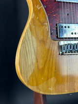 Close-up of a guitar's wooden body and fretboard on a dark background