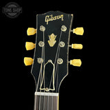 Gibson guitar headstock with yellow tuning pegs on a black background