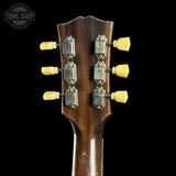 Close-up of a guitar headstock with tuning pegs on a black background, featuring 'Tone Shop' branding.