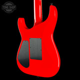 The rear view of a bright red electric guitar against a solid black background, showing the glossy body finish and black hardware plates.