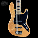 A natural wood five-string electric bass guitar with a black pickguard and chrome hardware, shown against a solid black background with a Tone Shop watermark in the top left corner.