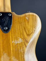 Close-up of a guitar's wooden body with a brand logo on a dark background