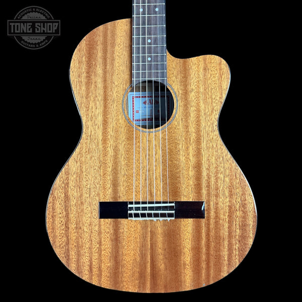 Acoustic guitar with a black pickguard on a black background, featuring the Tone Shop logo.