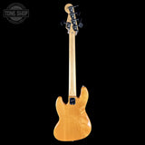 A natural wood electric bass guitar shown from the back against a solid black background, with a Tone Shop watermark in the upper left corner.