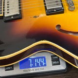 Guitar being weighed on a digital scale with a display showing weight.