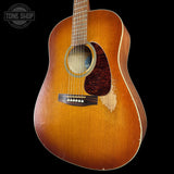 A vintage acoustic guitar with a natural sunburst finish, shown from a front-facing angle against a solid black background. The brand 'Tone Shop' is watermarked in the upper left corner.