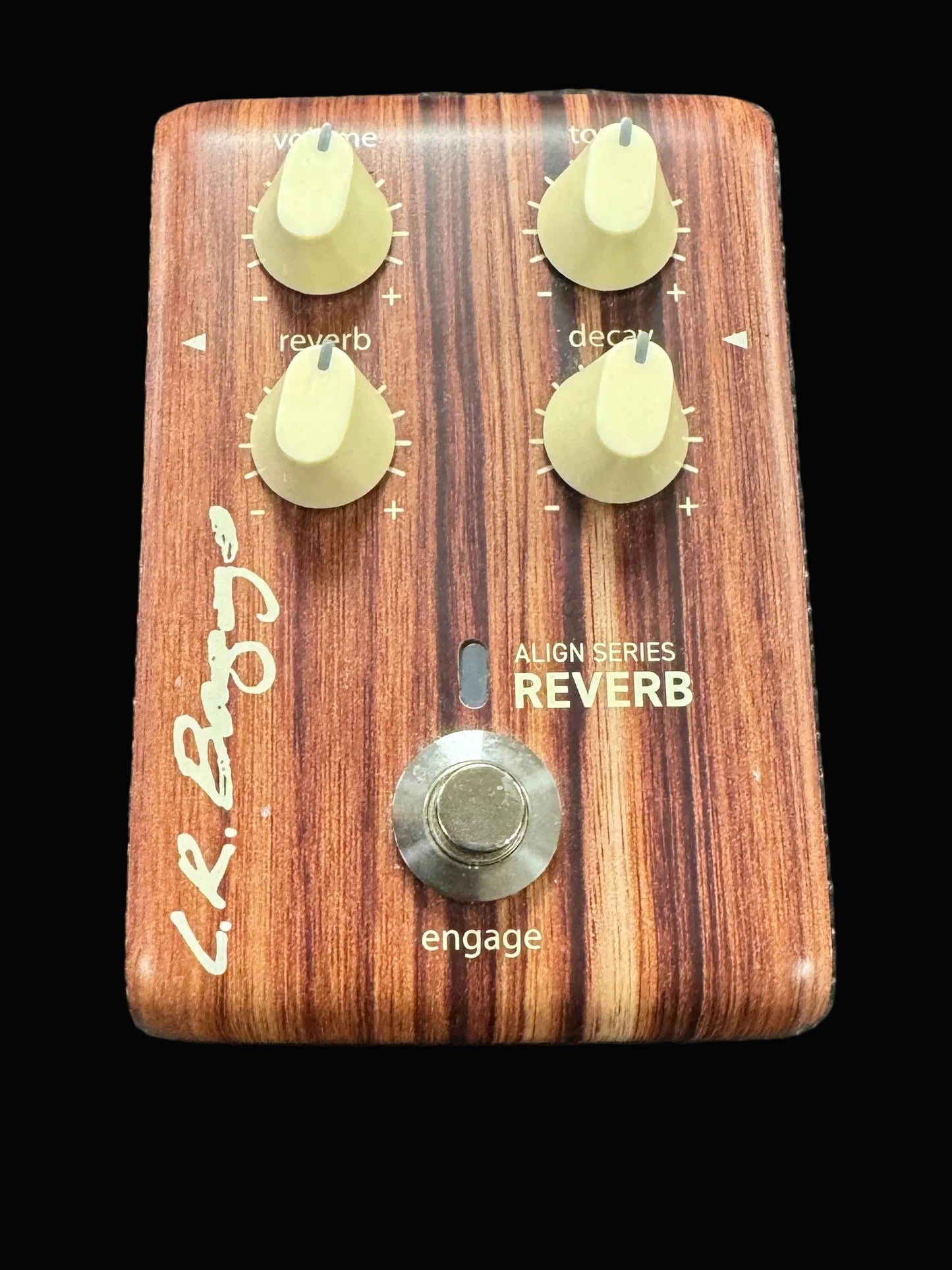 Wooden guitar effects pedal with knobs and a button on a textured surface