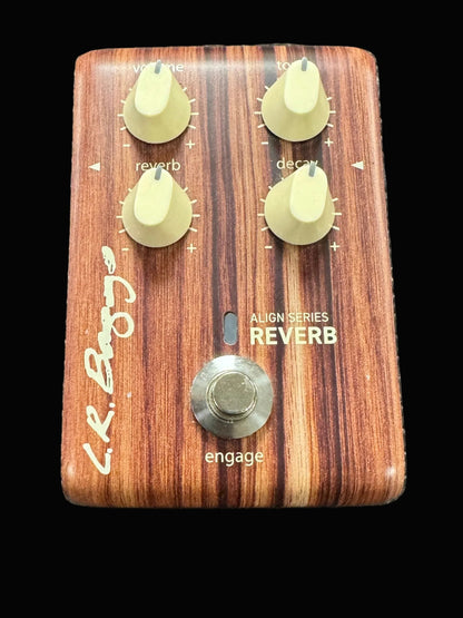 Wooden guitar effects pedal with knobs and a button on a textured surface