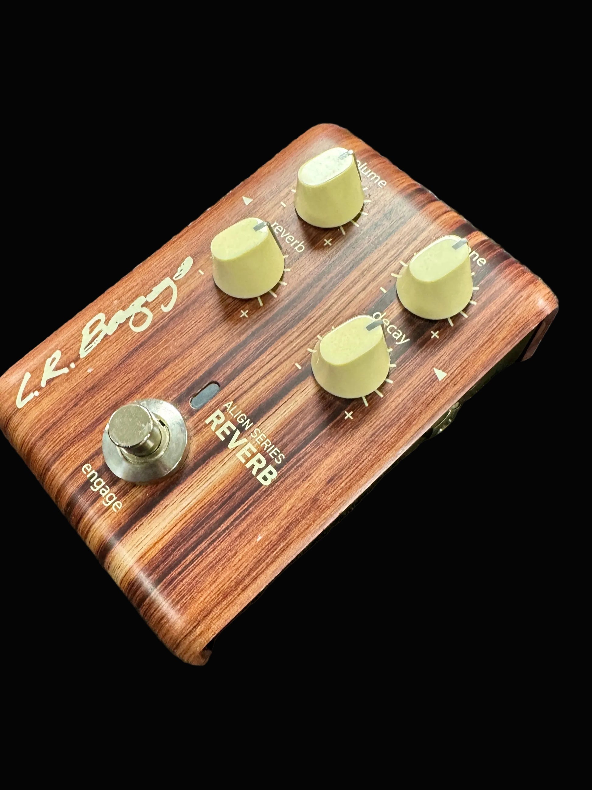 Wooden guitar effects pedal with four knobs on a textured surface
