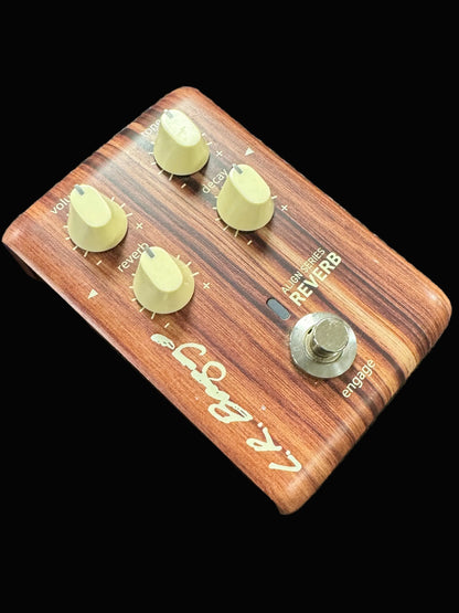 Wooden guitar effects pedal with control knobs on a textured surface