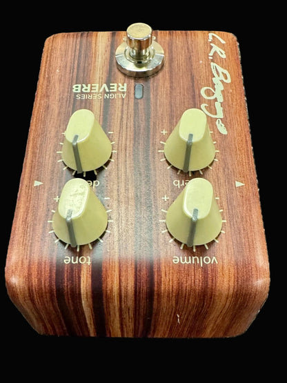 Wooden guitar effects pedal with four knobs on a textured surface