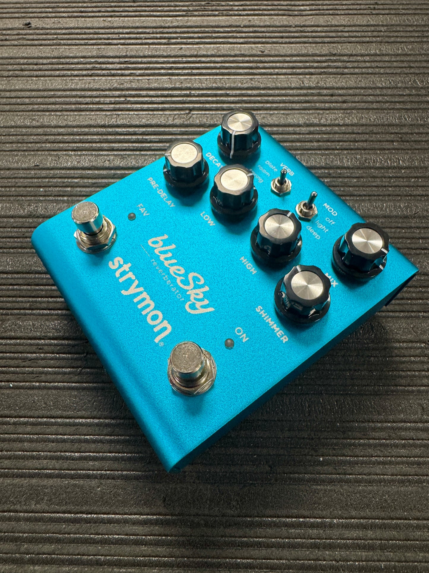 Blue Strymon guitar effects pedal on a textured surface