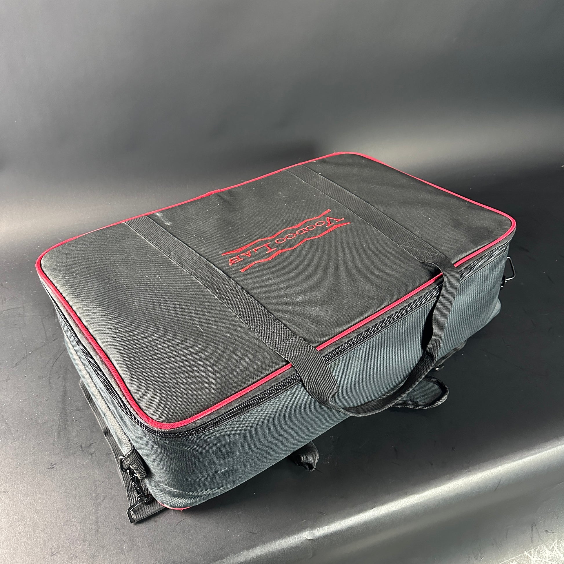 Gray carrying case with red trim and logo on a gray background