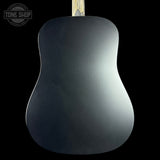 The back of a matte black acoustic guitar, showing a smooth dark finish and a light wood neck at the top, set against a solid black background with a Tone Shop watermark in the upper left.
