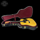 Acoustic guitar in an open case with 'Tone Shop' logo.