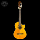 A classical acoustic guitar with a natural wood finish and cutaway body, shown vertically against a solid black background. A circular 'TONE SHOP' watermark is visible in the top-left corner.