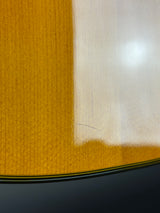 Close-up of a guitar body showing a bright yellow-orange sunburst finish transitioning to a lighter cream edge, with a glossy reflective surface and a dark lower section.