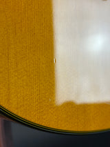 Close-up of a glossy yellow-gold wooden surface with a white reflective area and a dark edge visible on the right.