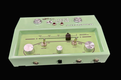 Green electronic pedal with various controls on a gray background