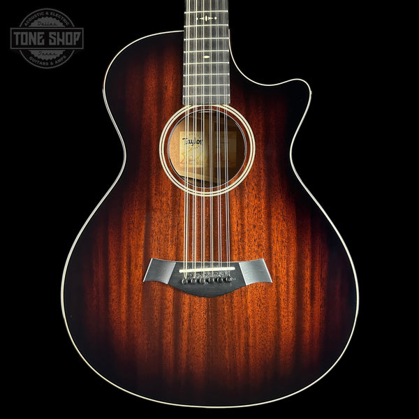 Taylor acoustic guitar with a cutaway body, featuring a rich sunburst finish that transitions from bright amber-orange to dark brown wood grain, shown against a solid black background.