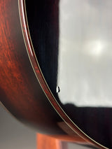 Close-up of a glossy dark brown wooden instrument body with a thin light-colored edge stripe and a small reflective highlight.