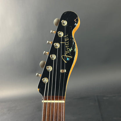 Guitar headstock with Fender logo on a gray background