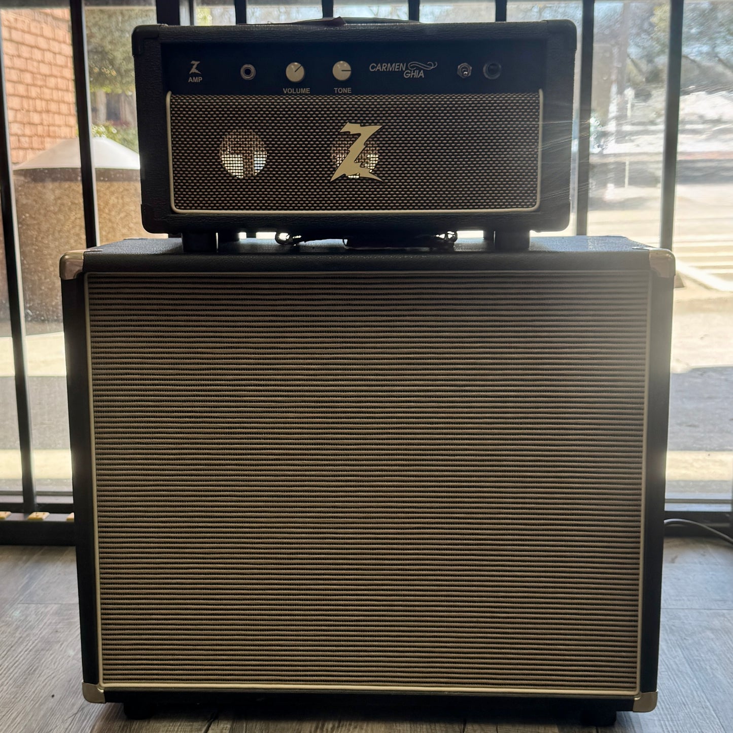 Guitar amplifier with 'Z' logo on top, placed against a glass door background.