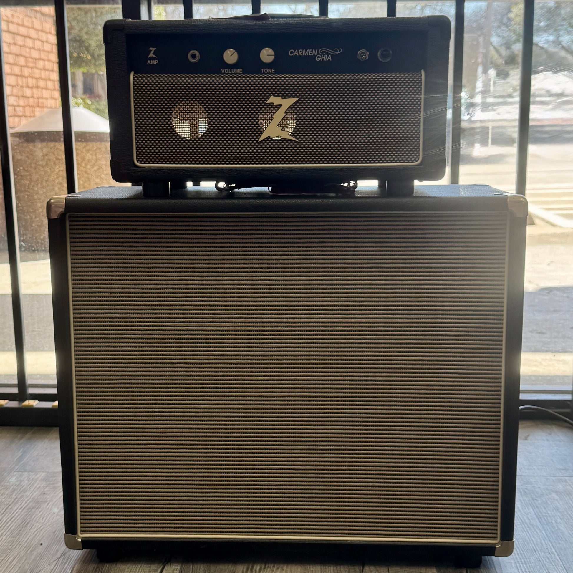 Guitar amplifier with 'Z' logo on top, placed against a glass door background.