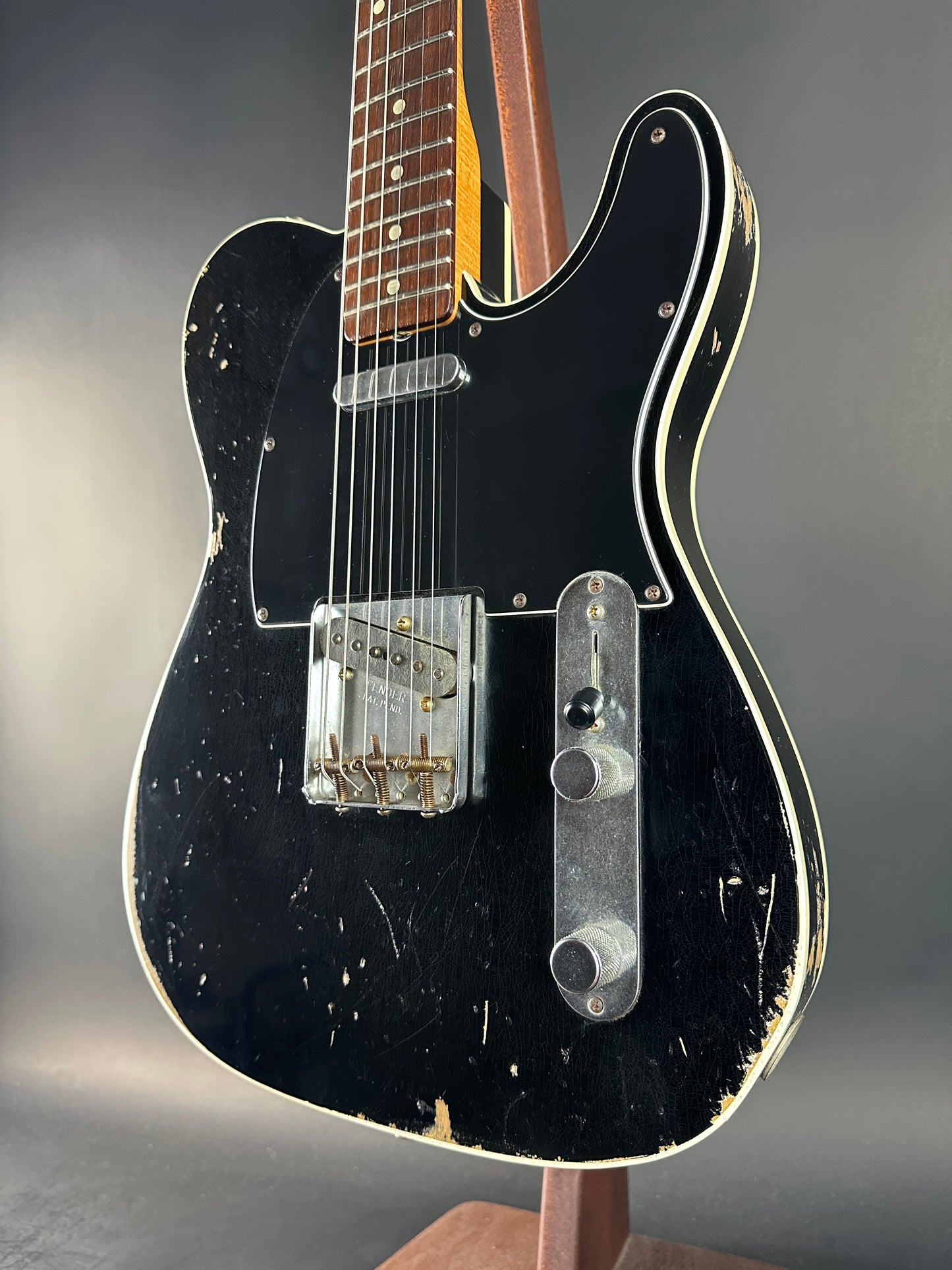 Black electric guitar with a worn finish on a gray background