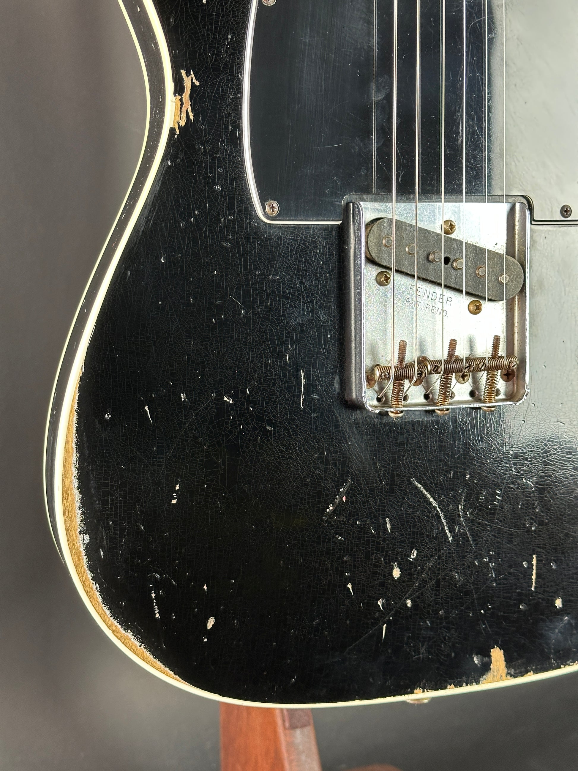 Close-up of a black electric guitar with visible wear on the body.