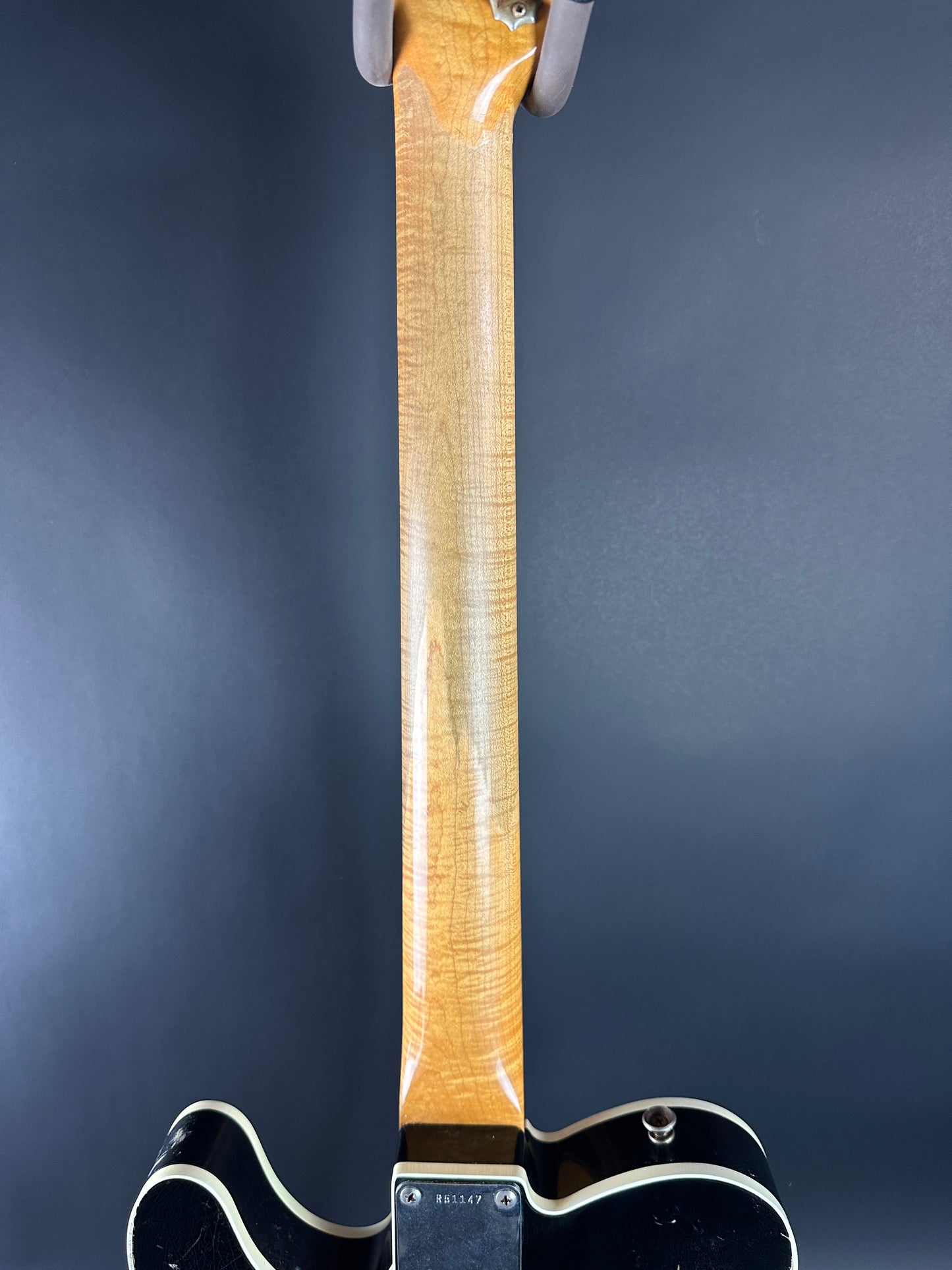Close-up of a guitar's neck and headstock on a dark background