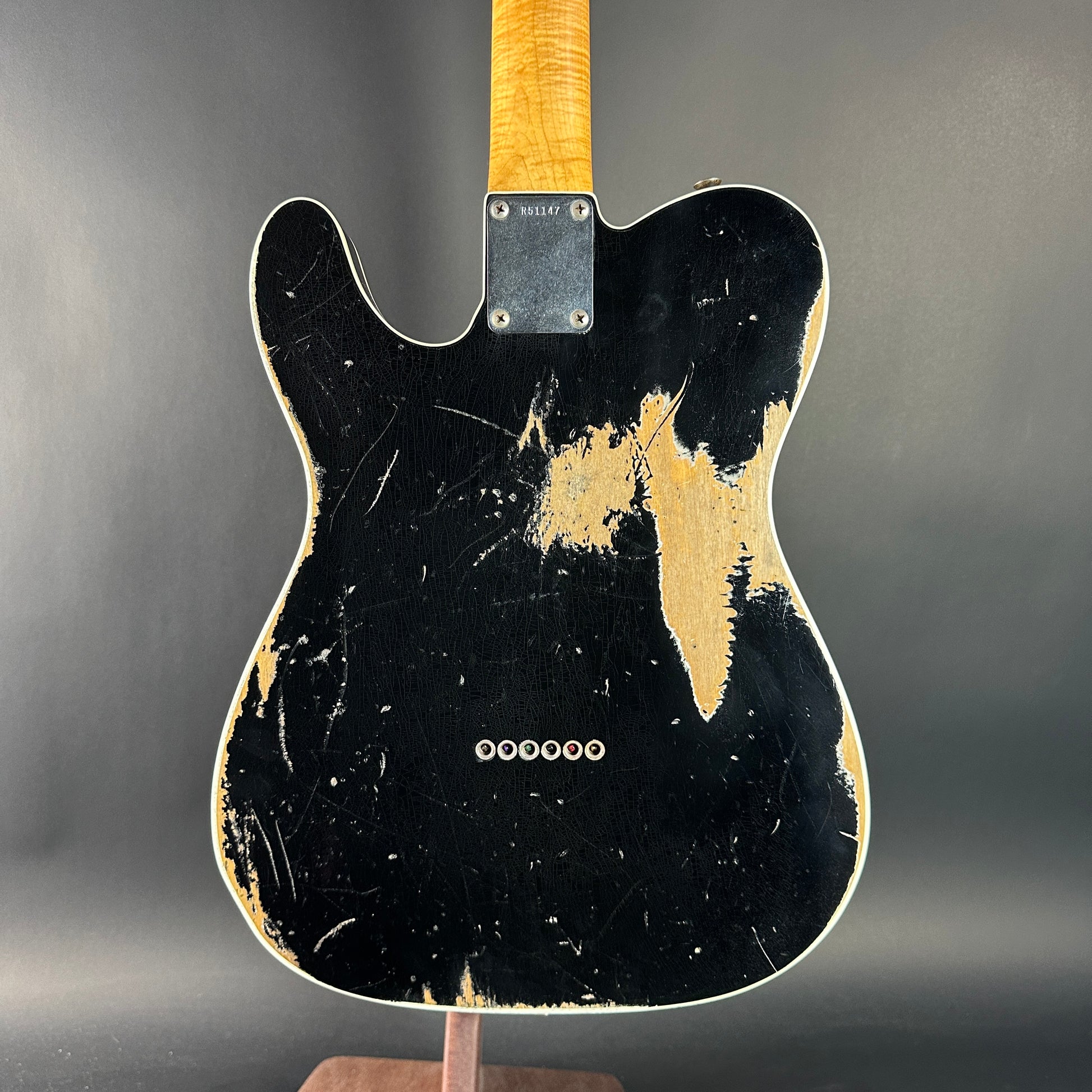 Black electric guitar with a distressed finish on a gray background