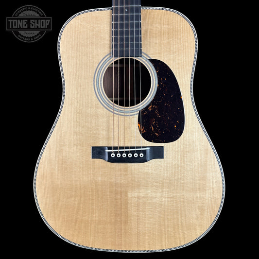 Acoustic guitar with a natural wood finish on a black background, featuring the Tone Shop logo.
