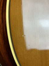 Close-up detail of a wooden instrument body showing the glossy varnish, wood grain, a black and white stripe, and a cream-colored edge.
