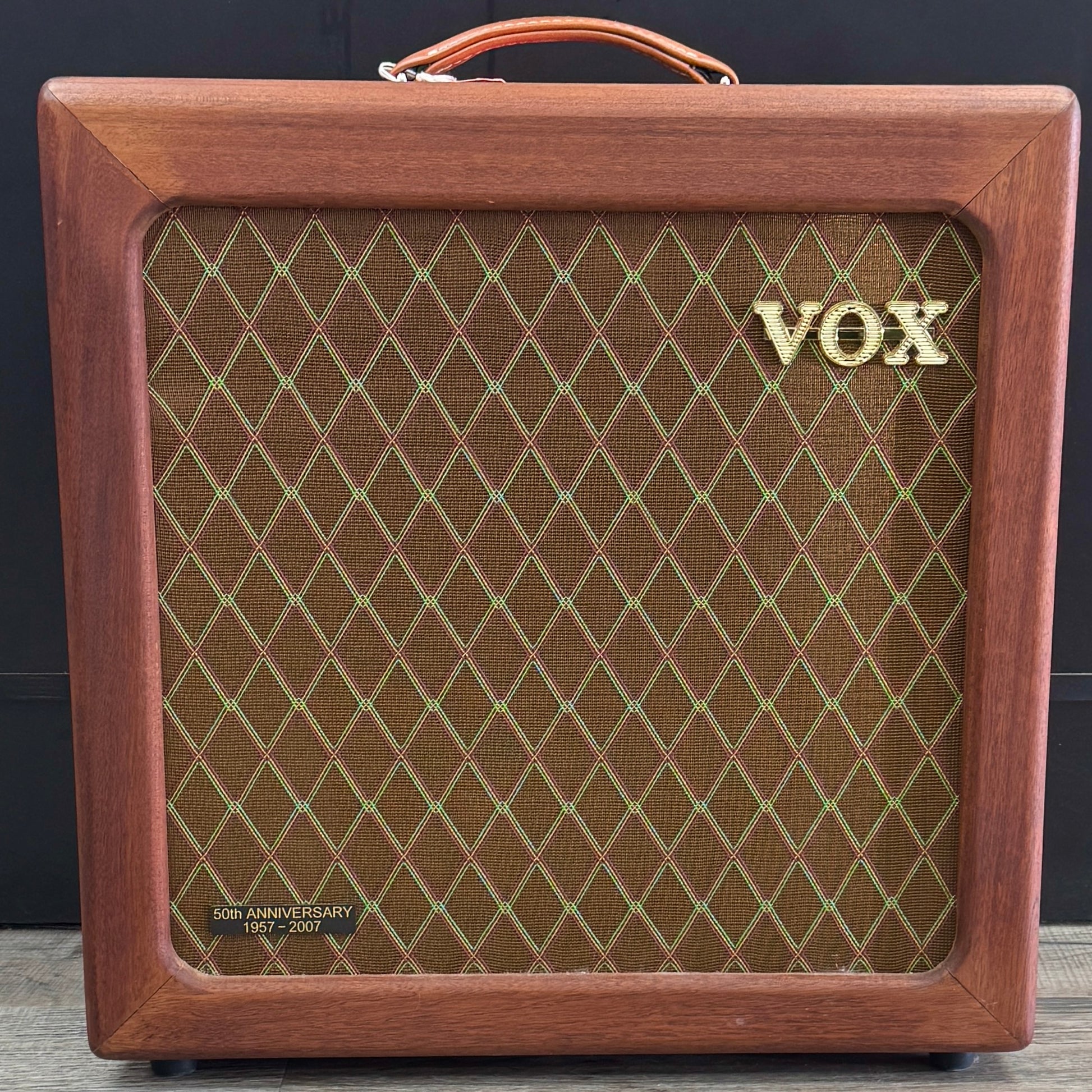 Wooden VOX amplifier with grid pattern on a dark background