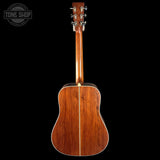 Back view of a wooden acoustic guitar on a black background with 'Tone Shop' logo.