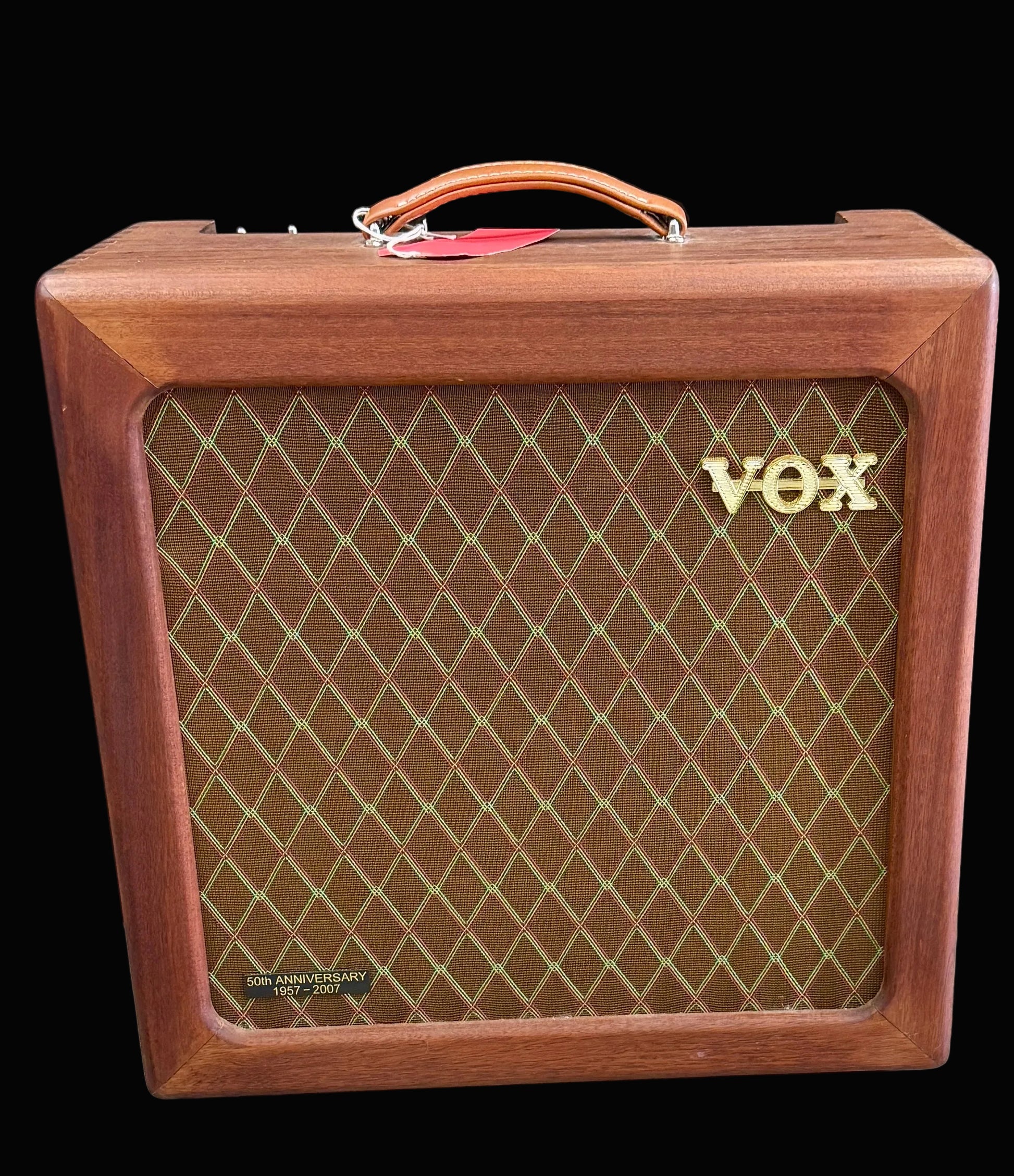 Wooden VOX amplifier with brown grille and gold logo on a dark background
