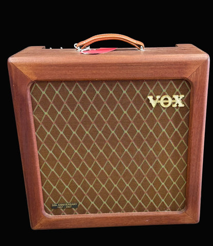 Wooden VOX amplifier with brown grille and gold logo on a dark background