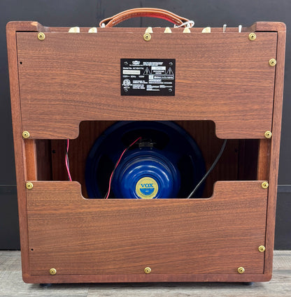Wooden guitar amplifier with a blue speaker and visible Vox logo.