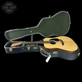 Acoustic guitar in a hard case with 'Tone Shop' logo in the corner.