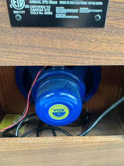 Blue electric drill with a Vox logo on a wooden surface