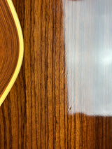 Close-up of a polished wooden surface with visible wood grain and a small curved light-colored edge at the bottom.