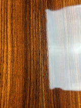 Close-up of a glossy brown wood-grain surface with a light reflection near the top.