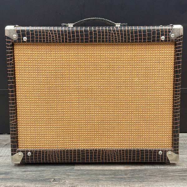 Vintage-style guitar amplifier with brown grille and black frame on a wooden surface.