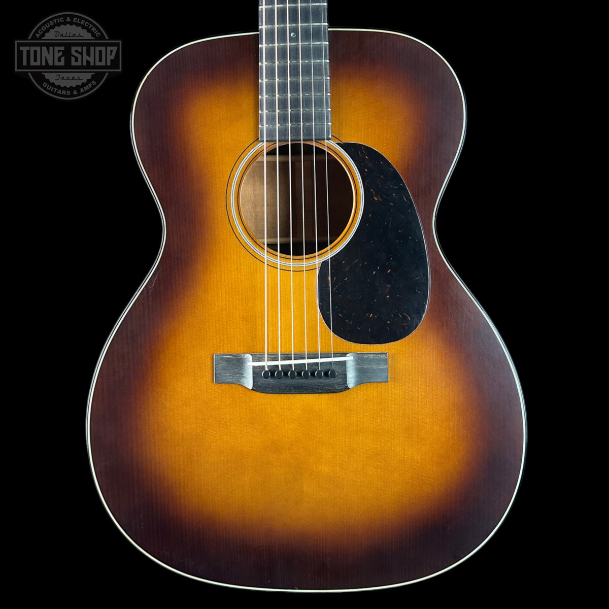 Acoustic guitar with a sunburst finish on a black background, featuring the Tone Shop logo.
