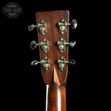 Close-up of a guitar headstock with tuning pegs on a black background, featuring the Tone Shop logo.