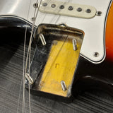 Close-up of a guitar's bridge and strings with a worn soundhole cover.