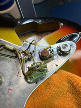 Close-up of a guitar's control panel with wiring and components.
